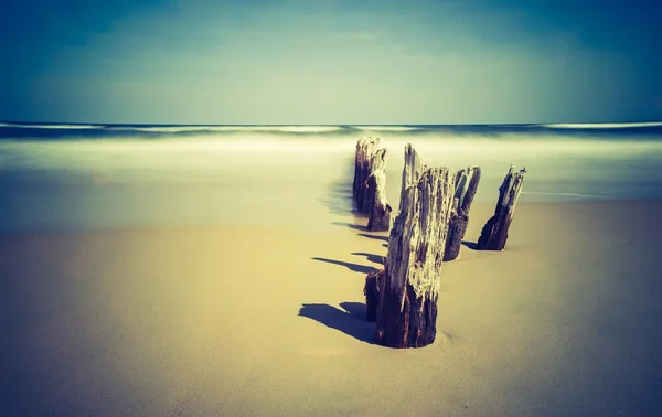 Foto vintage de orilla del mar con rompeolas de madera — Foto de Stock