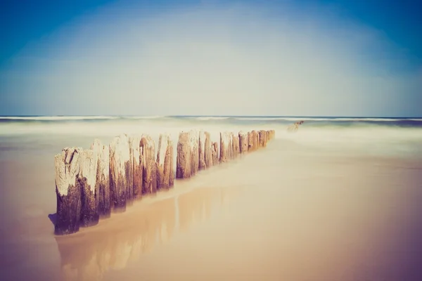 Vintage photo of seashore with wooden breakwater — Stock Photo, Image