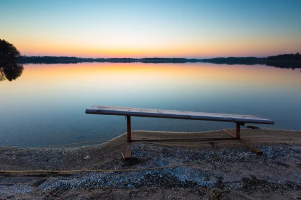 Lake landscape at sunset with bench — Stock Photo, Image