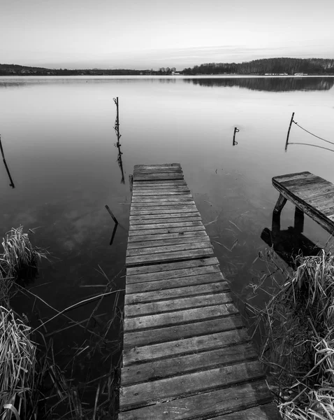 Black and white lake landscape with small wooden pier — Stock Photo, Image