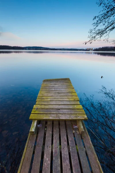 Lake landscape with small old wooden pier photographed on long exposure Royalty Free Stock Images