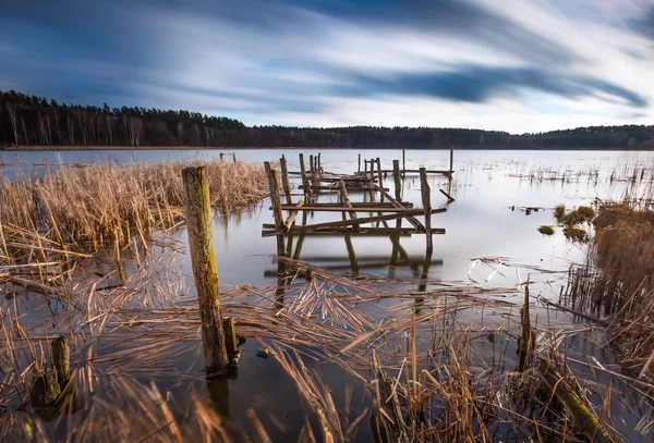 Paisaje del lago con pequeño muelle de madera viejo fotografiado en exposición larga —  Fotos de Stock