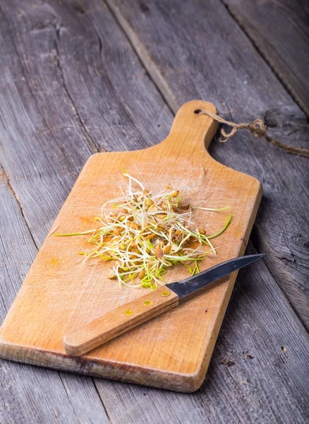Lentejas frescas y brotes de trigo en la tabla de cortar . — Foto de Stock