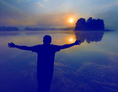 Göl üzerinde güneşin doğuşunu izleyen adamım. İnsan silueti. 