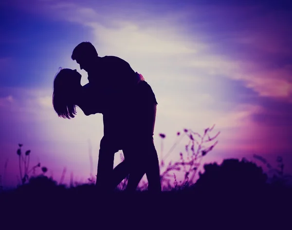 Silhouettes of hugging couple against the sunset sky. Vintage mood. — Stock Photo, Image