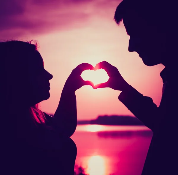 Пара в форме сердца с руками на берегу озера. — стоковое фото