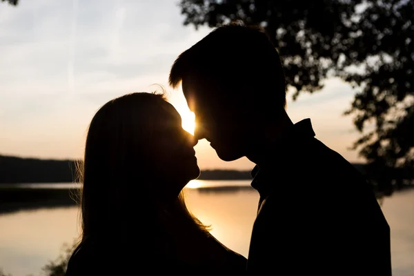 Siluetas de pareja abrazada contra el cielo del atardecer — Foto de Stock