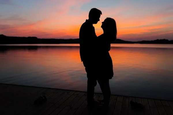 Silhouettes of hugging couple against the sunset sky — Stock Photo, Image