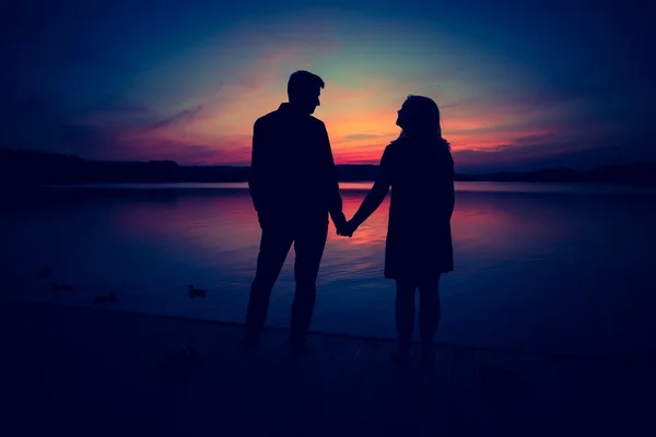 Silhouettes of hugging couple against the sunset sky — Stock Photo, Image