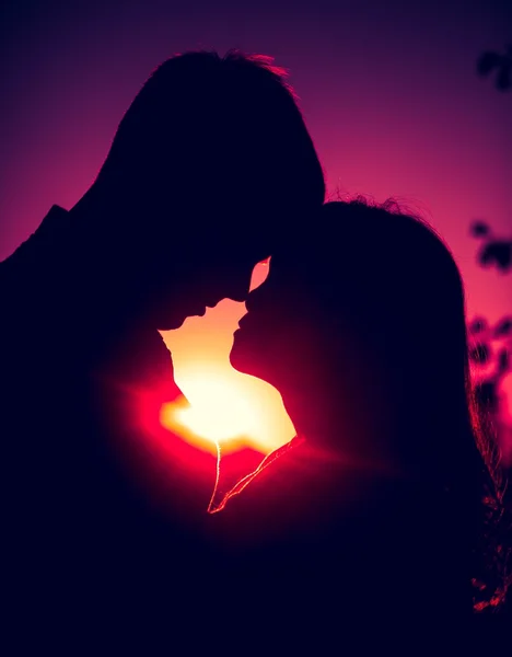 Silhouettes of hugging couple against the sunset sky — Stock Photo, Image