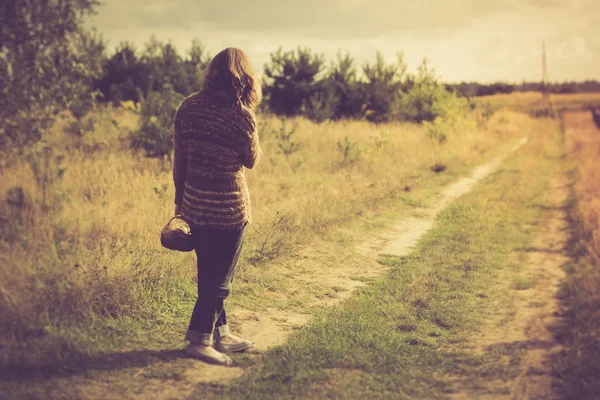 Fille en pull marchant par la route herbeuse rurale — Photo