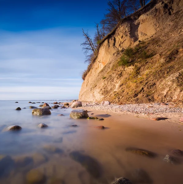 Klippe am Meeresufer bei Sonnenaufgang. Ostsee Langzeitbelichtung Foto — Stockfoto