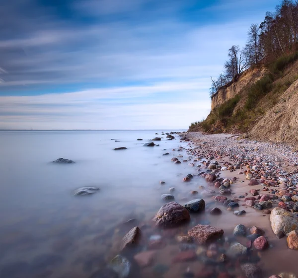 Klippe am Meeresufer bei Sonnenaufgang. Ostsee Langzeitbelichtung Foto — Stockfoto