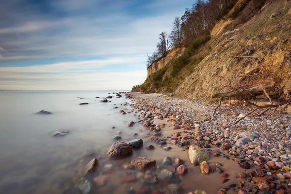 Klippa på havsstranden vid soluppgången. Östersjön lång exponering Foto — Stockfoto