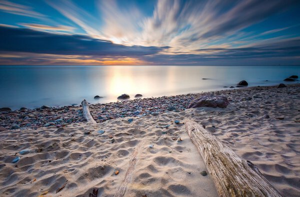 Rocky sea shore with driftwood at sunrise. Beautiful seascape