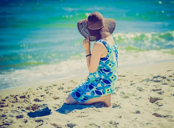 Wooman im Kleid sitzt am Ufer des Meeres. — Stockfoto