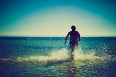 Deniz suyu Beach'te aracılığıyla koşan adam silüeti