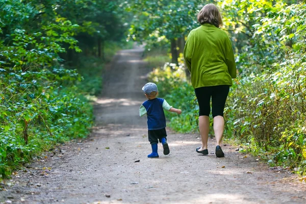 Little boy and mother running and playing in forest at summer.