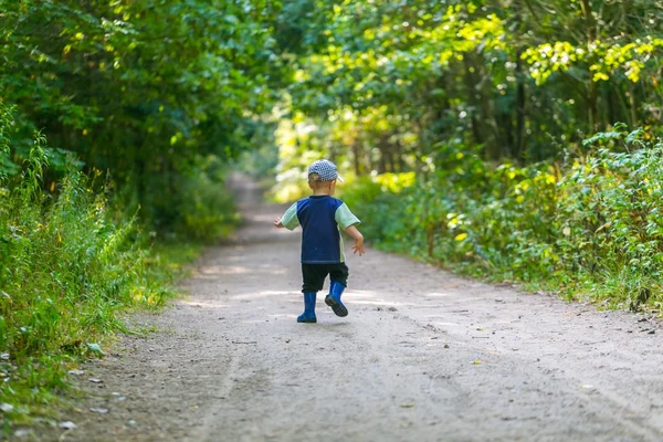 Niño corriendo y jugando en el bosque en verano . — Foto de Stock