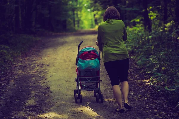 Vintage foto van moeder met wandelwagen en baby wandelen door zomer bospad — Stockfoto