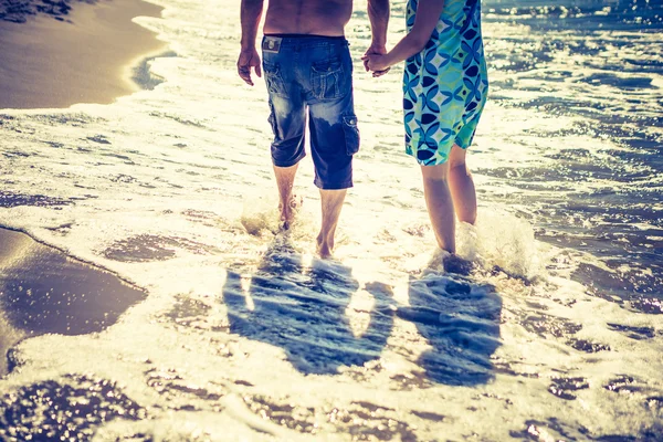 Pareja caminando por la orilla del mar a la luz del día — Foto de Stock