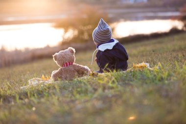 Çocuk ve oyuncak ayı gün batımını izlemek