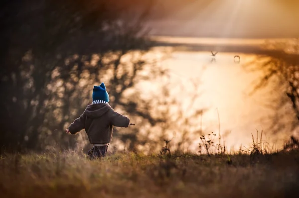 Niño jugando al aire libre en la orilla del lago . — Foto de Stock