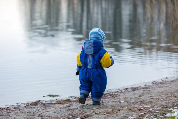 Niño jugando al aire libre en la orilla del lago congelado . — Foto de Stock