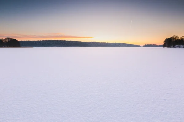 Sunset sky over frozen and snowy lake. — Stock Photo, Image
