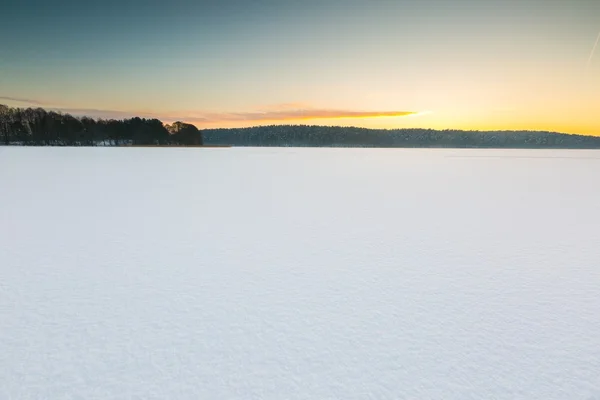 凍結し、雪に覆われた湖の夕焼け空. — ストック写真