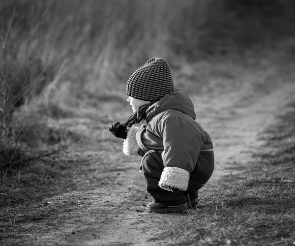 Giovane ragazzo felice che gioca all'aperto sulla strada di campagna. Foto in bianco e nero — Foto Stock