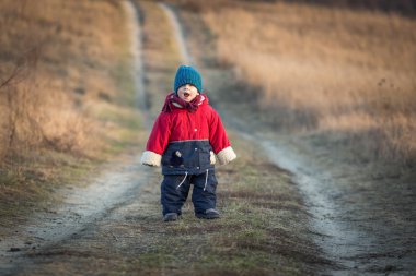 Young happy boy playing outdoor on country road