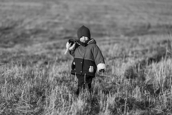 Kleiner glücklicher Junge, der im Frühling draußen spielt. schwarz-weiß — Stockfoto