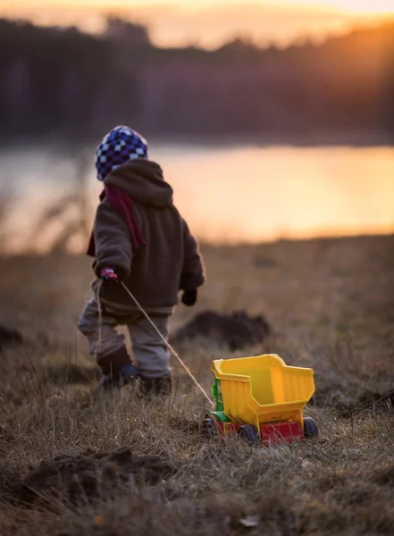 Niño jugando al aire libre con un coche de juguete . — Foto de Stock
