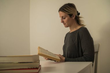 Masada oturmuş kitap okuyan bir kadının yakın çekimi.