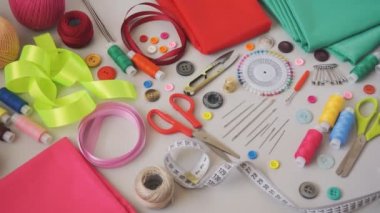 Dikiş dikmek için malzeme ve aksesuarlar. Dikiş iplikleri, iğneler, iğneler, makas, kumaş, düğmeler ve dikiş santimetresi. Üst görünüm