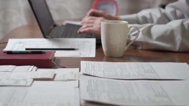 自宅のオフィスで働いてる男が職場の書類にコーヒーをこぼした 白いカップのコーヒーは書類でテーブルの上にこぼされる — ストック動画