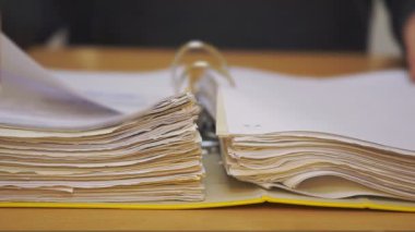 Dosyayı belgelerle birlikte aç. Girişimci mali belgeleri inceler. Sayfayı okurken parmakları tutan eller