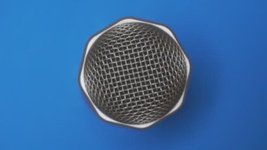 Mavi arka planda mikrofon yakın plan. Üst görünüm