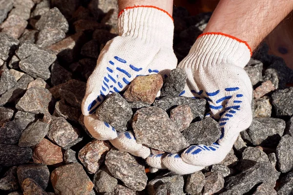 Crushed stone in hands. Crushed rock in the hands of a worker