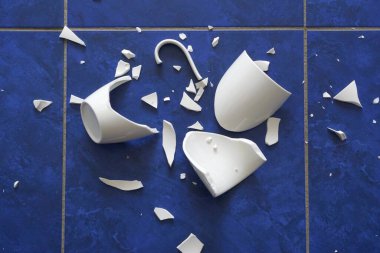 Broken cup. Shards from the cup are scattered on the floor clipart