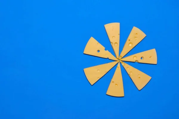 Slices of cheese on a blue background. Top view