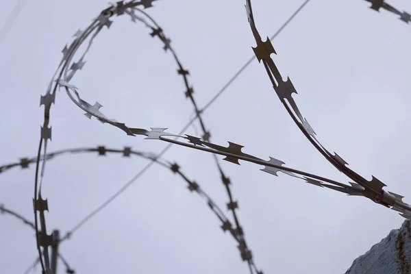 Barbed metal wire against a cloudy sky