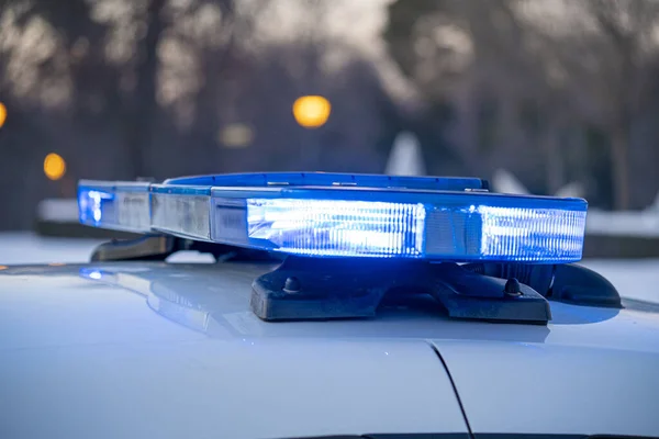 Polis arabasının tepesindeki mavi ışıklar. Arka plan bulanık. Işıklar da bokeh etkisi yapıyor.