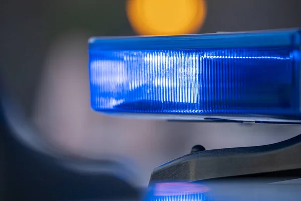 Polis arabasının tepesindeki mavi ışıklar. Arka plan bulanık. Işıklar da bokeh etkisi yapıyor.