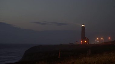 Gece Portekiz 'de bir plajda deniz feneri parlıyor.