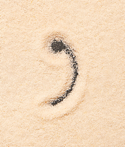 Comma symbol written on sand