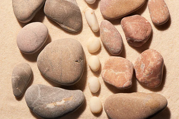 Pedras marinhas tonificadas rosa e cinza separadas por branco na areia — Fotografia de Stock