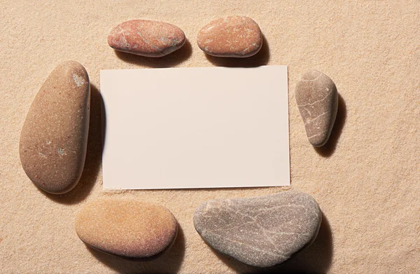 Quadro retangular de pedras marinhas com cartão de visita branco na areia — Fotografia de Stock
