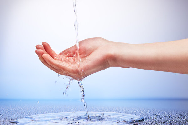 Water falling in womans hand on white and blue